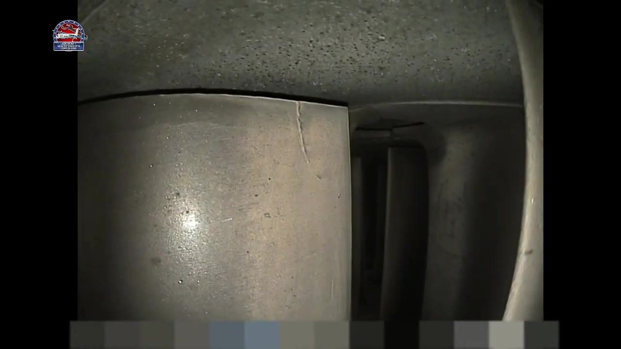 Metallic component with a visible crack at the top edge, adjacent blades visible in the background