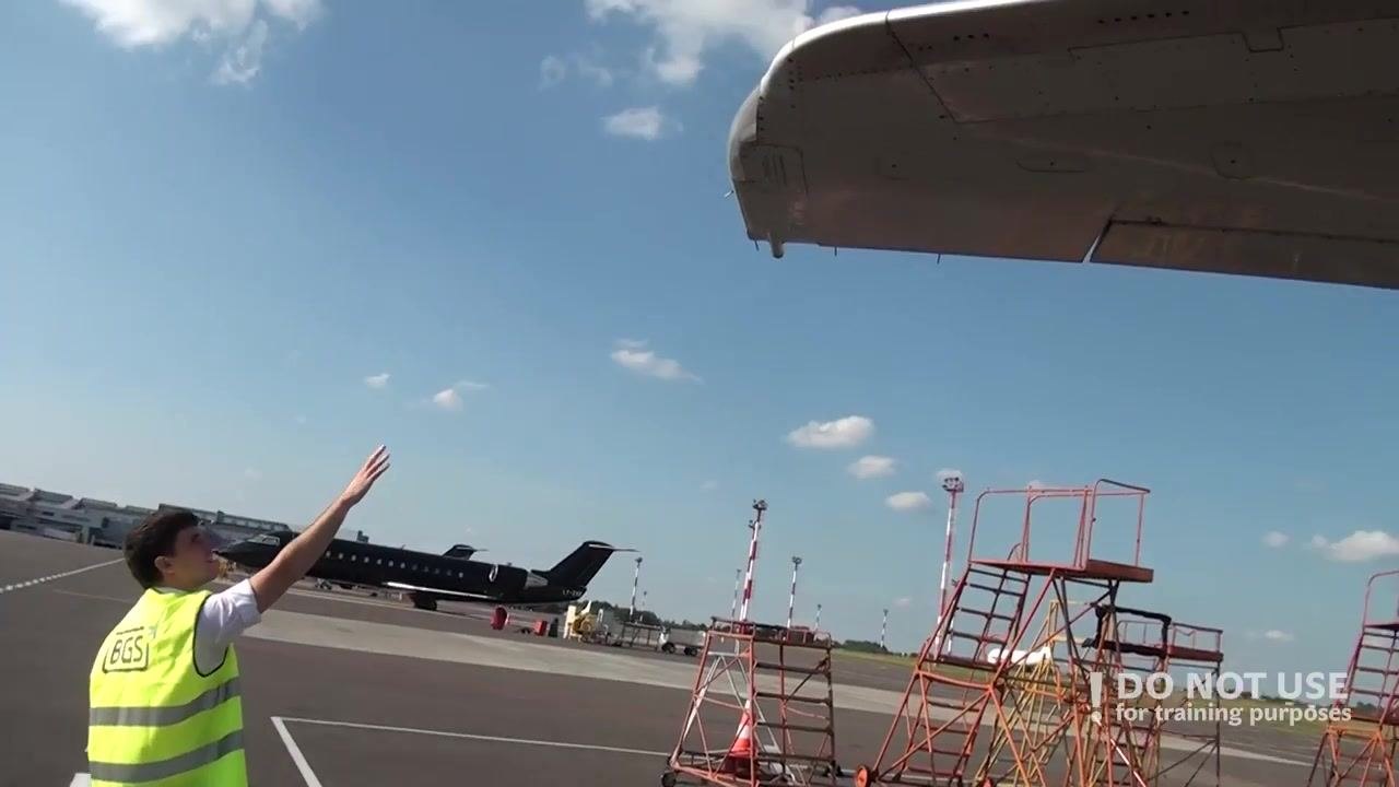 Person reaching up toward the wingtip, inspecting static dischargers, with maintenance stands visible in the background.