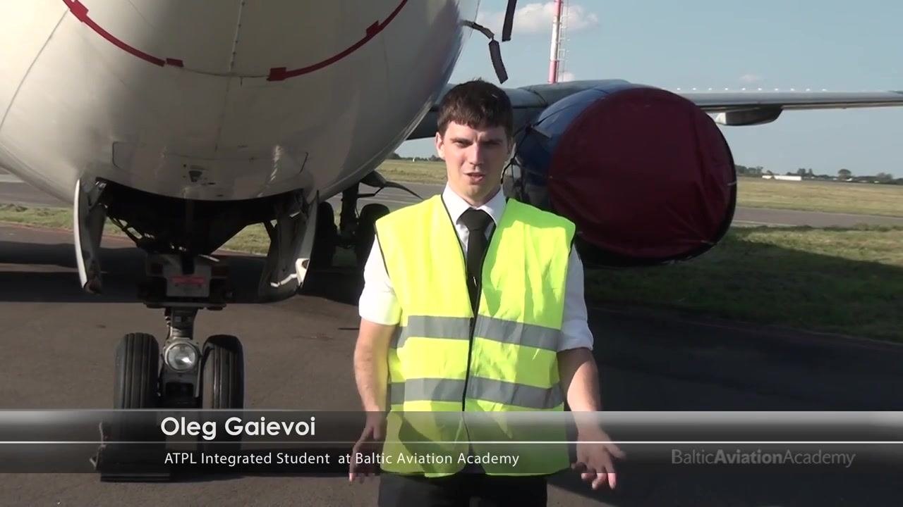 Inspector in high-visibility vest standing in front of aircraft nose, name and title overlay visible.