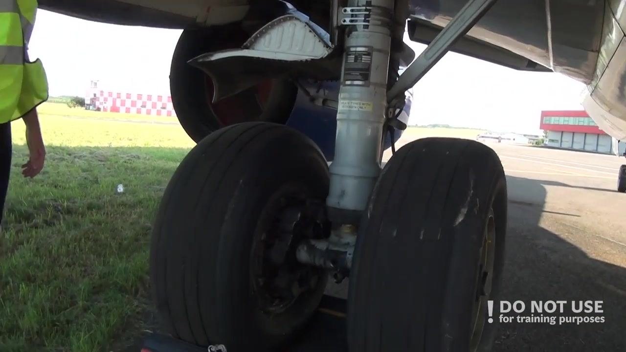 Inspector walking along the left aft fuselage, arm raised, checking doors and surface condition.