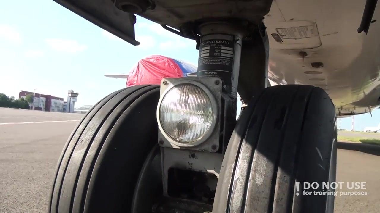 Close-up of the nose gear assembly, showing the wheels, exterior light, and steering mechanism.