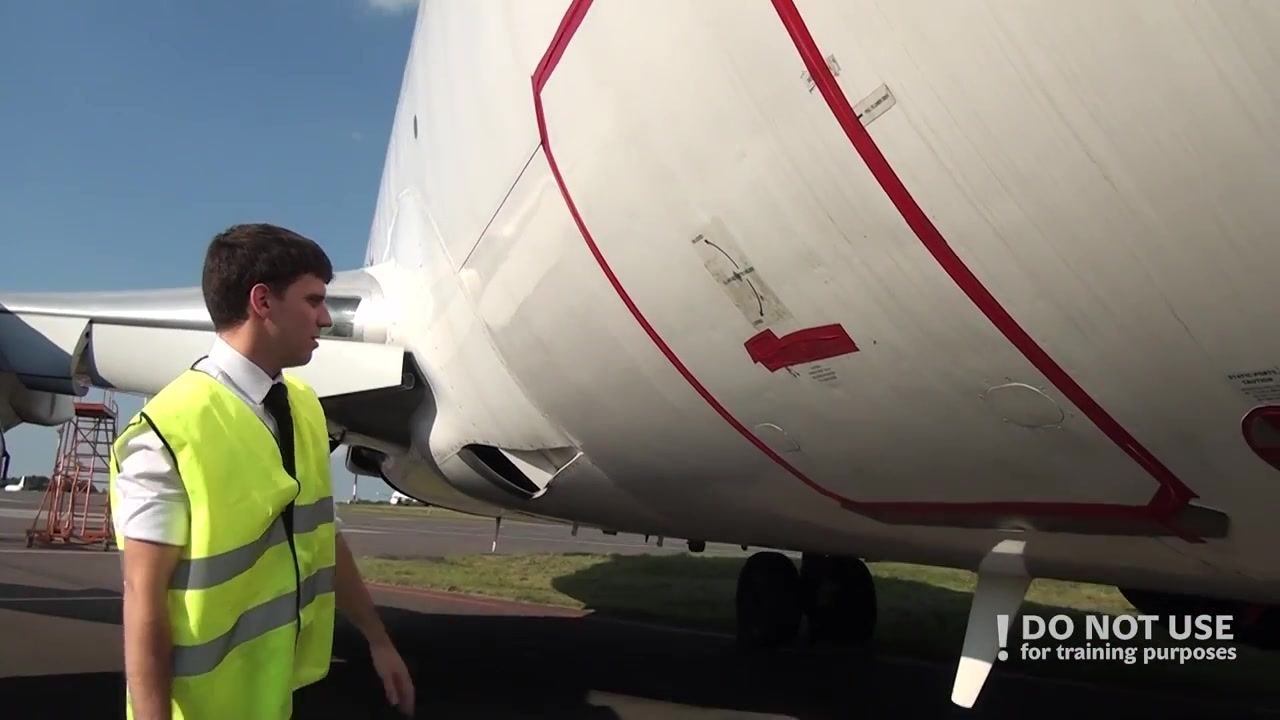 Person standing near the right front fuselage, inspecting the closed cargo door and antenna area outlined in red.