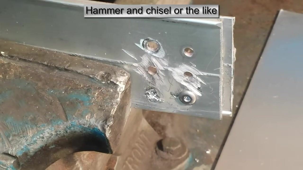 The rivet head sheared off, leaving a rough hole and metal debris. The chisel or screwdriver is no longer in frame.