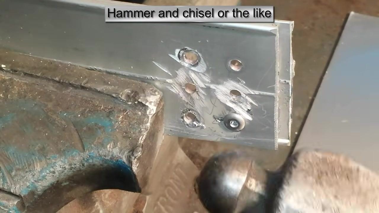 A hammer positioned near the workpiece, ready to strike the chisel or screwdriver, with several rivet holes and tool marks visible. On-screen text: "Hammer and chisel or the like."