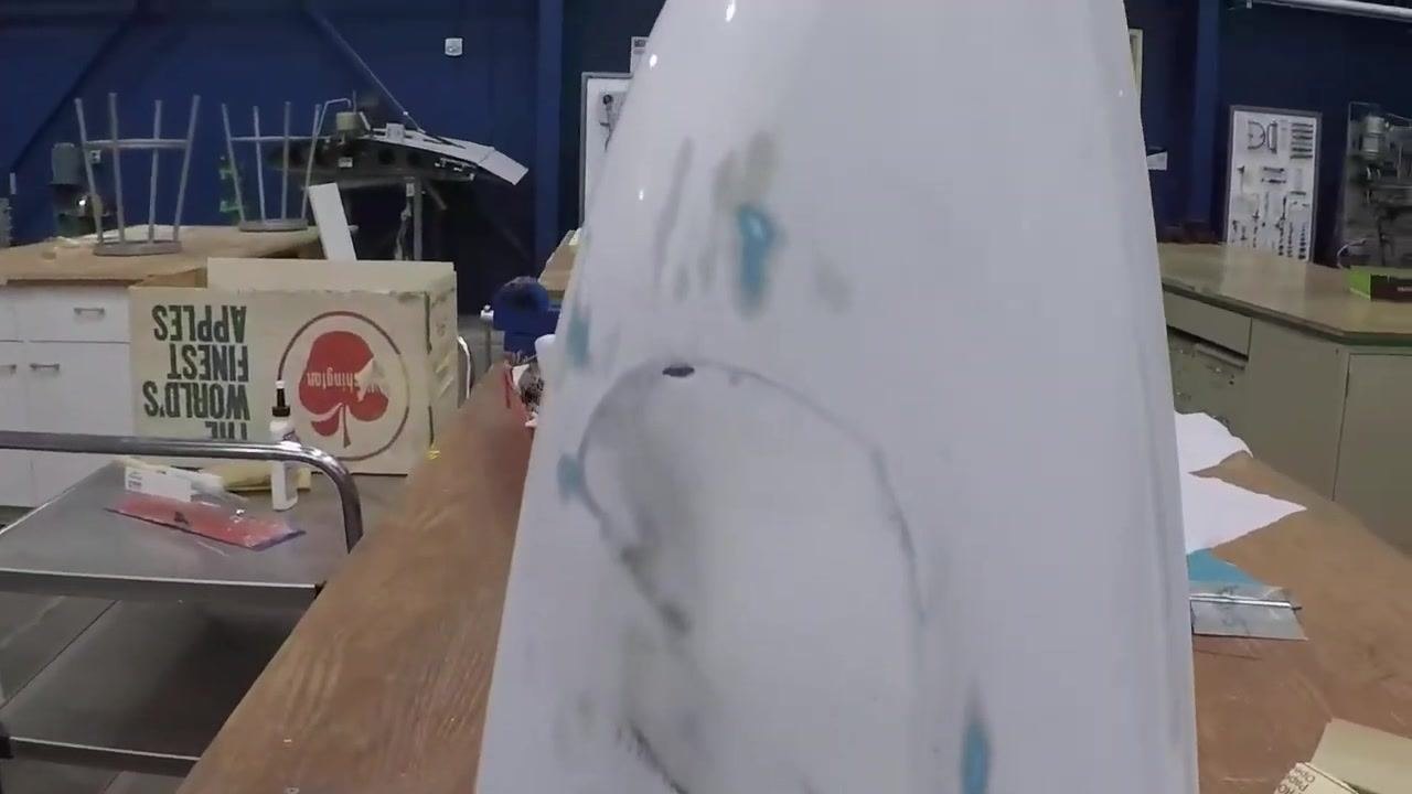 A close-up view of the tail cone on a workbench shows the repaired area filled with dry micro, with tools, sandpaper, and a sanding block visible nearby.