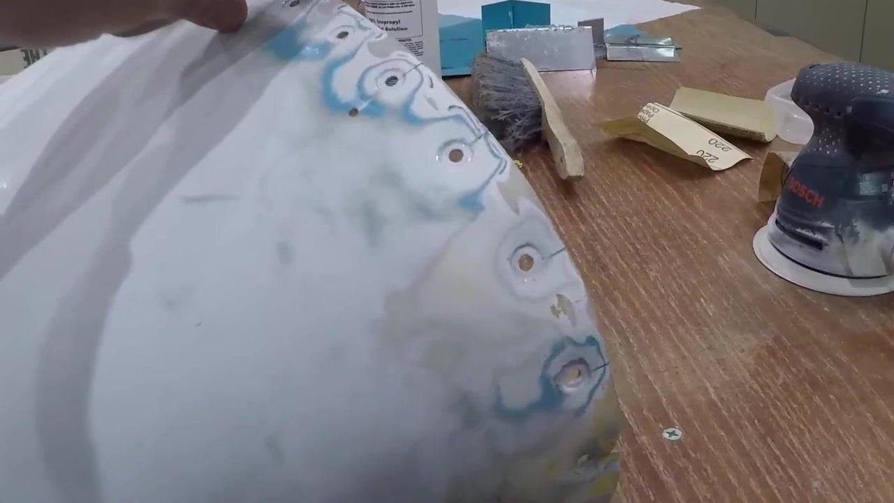 A close-up view of the sanded repair area on the tail cone shows smooth transitions and surface prep, with sandpaper and sanding tools visible on the workbench.