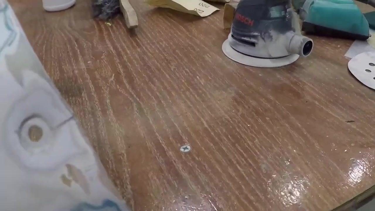 A close-up view of the lower portion of the tail cone shows the smooth, sanded surface and filled cracks, with the workbench and sanding tools visible.