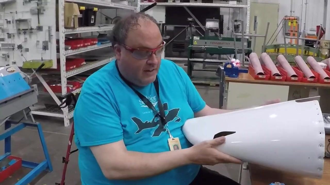 A hand holds the tail cone and points inside, indicating where cleaning and sanding will be performed before laying fiberglass.