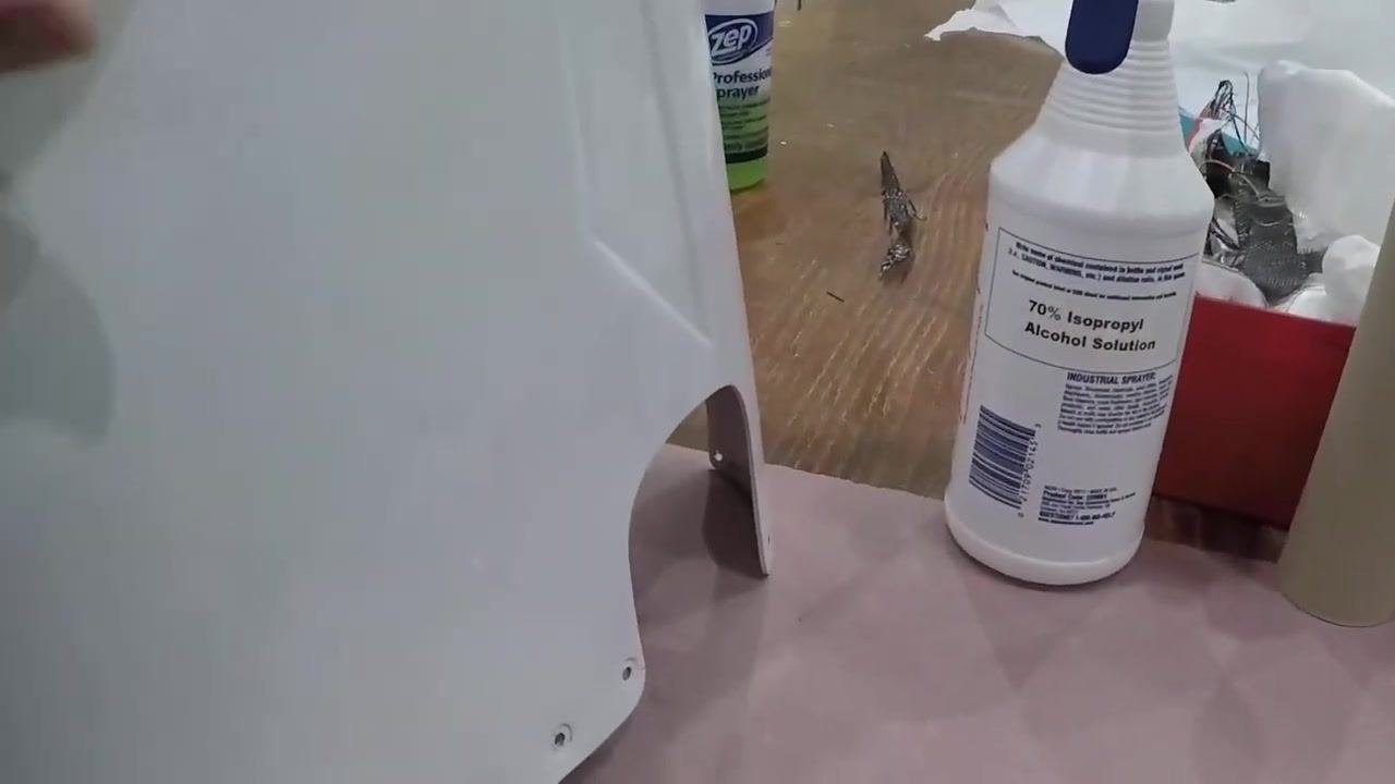 The tail cone stands on the workbench next to a bottle of 70% isopropyl alcohol solution, ready for cleaning before fiberglass application.