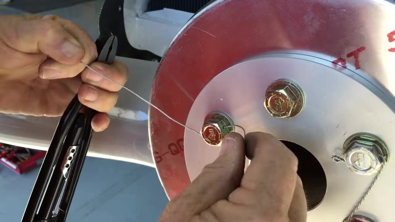 Threading and routing the safety wire through the bolt holes, maintaining correct direction and length