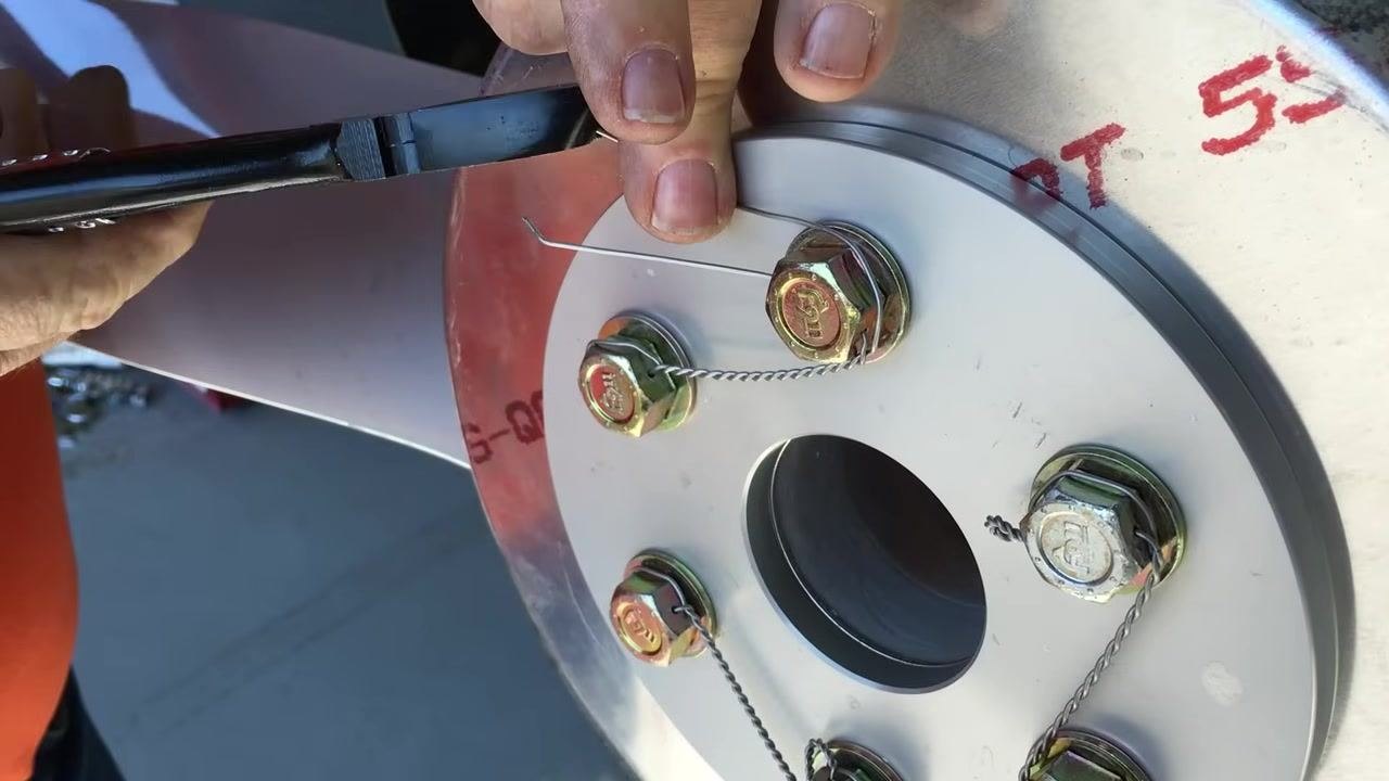 Bringing the tag end around and pulling it tight with pliers, preparing for final twisting