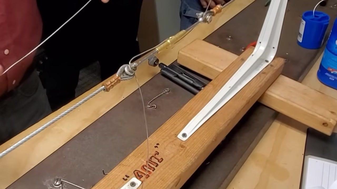 A person inserts the second piece of safety wire through the opposite horn of the turnbuckle, preparing for the double wrap.
