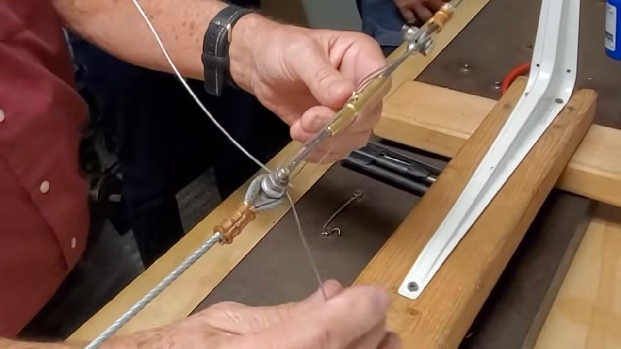 A person holds both safety wires, preparing to fold one over to complete the safety wire installation.