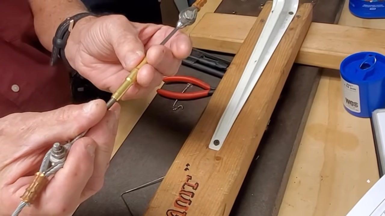 A person holds the cable assembly, visually inspecting the number of threads engaged on both ends.