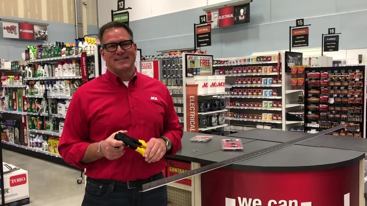 Yellow-handled rivet gun held up in a hardware store, with product shelves and signage in the background