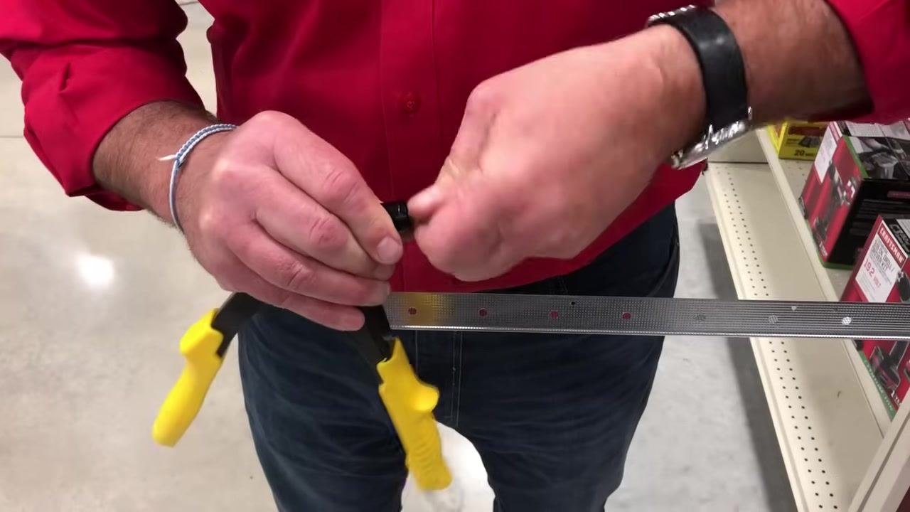 Rivet gun and a rivet held above a metal strip with pre-drilled holes