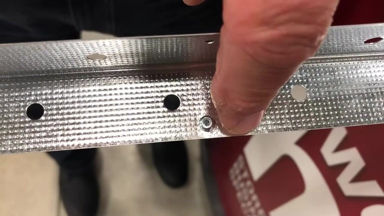 Rivet gun handles being squeezed with the mandrel about to break off, close-up on the tool and rivet in the metal strip