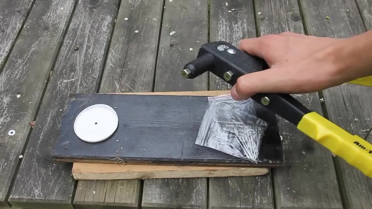 The user holding the riveter above the materials, ready to insert the rivet into the drilled hole, with the correct nozzle installed.