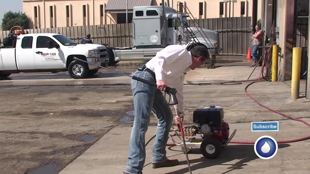 The unloader is adjusted while holding the spray gun, with the test gauge and equipment visible.