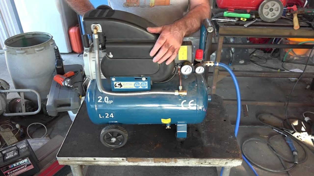 Close-up of a pressure gauge showing Kg/cm², KPa (bar), and Lb/in² (psi) scales, with a finger pointing to the current reading just above 2 Kg/cm²