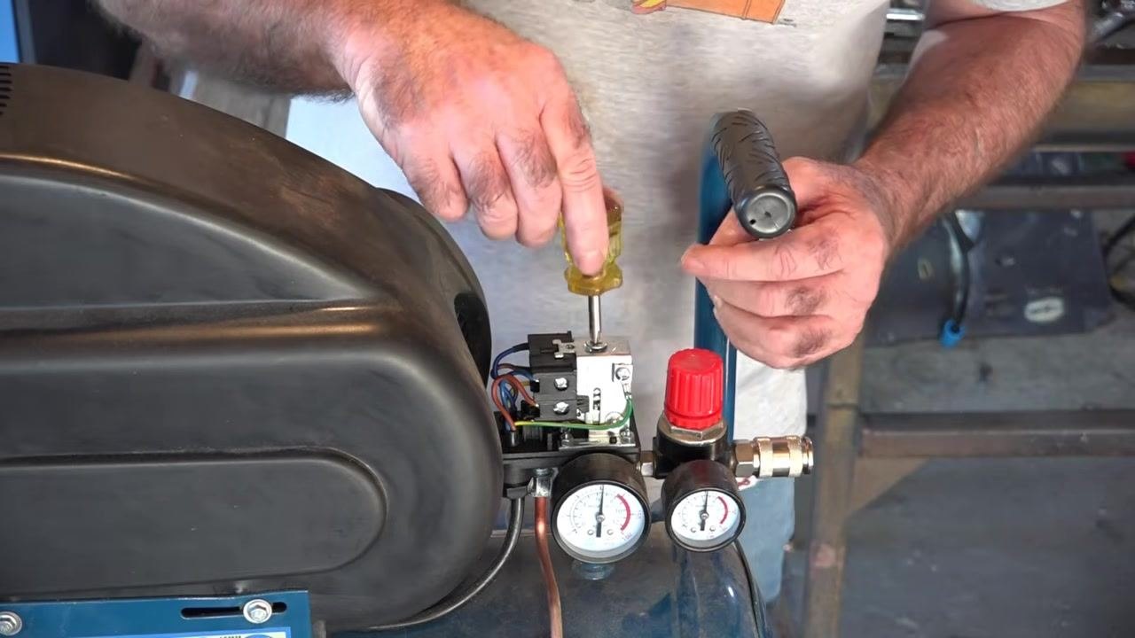 Close-up of the adjustment screw with "+" and "–" symbols marking the direction for increasing or decreasing pressure