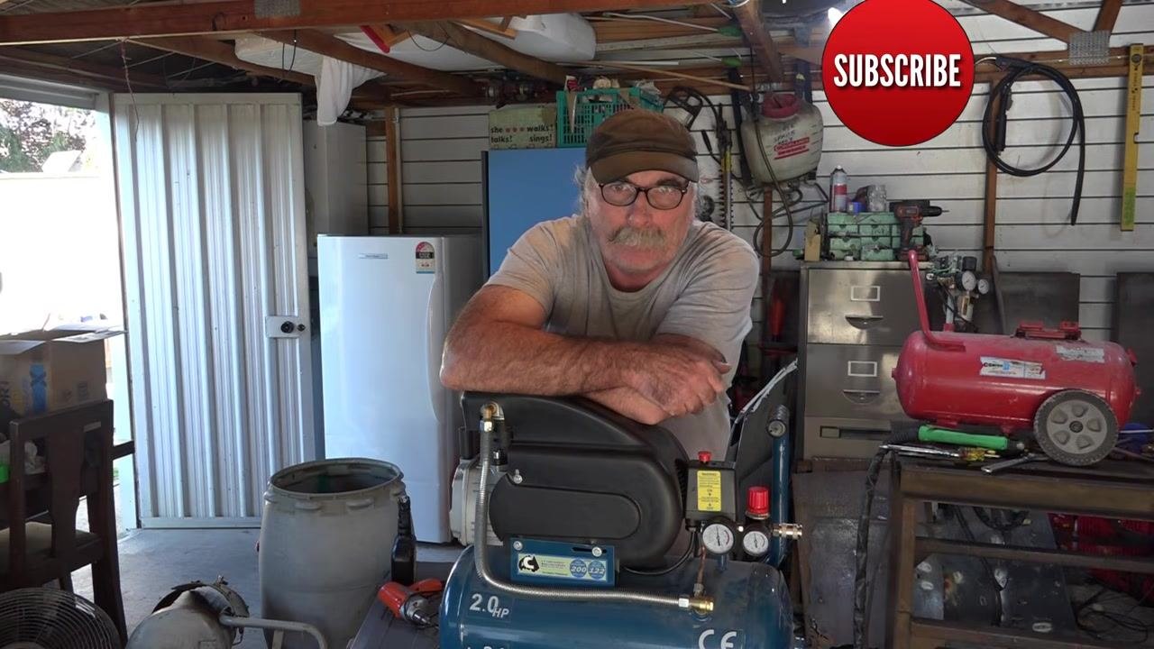 Operator in workshop, leaning on compressor, with a large red "SUBSCRIBE" button in the upper right, inviting viewers to comment and engage. Workshop tools and equipment visible.