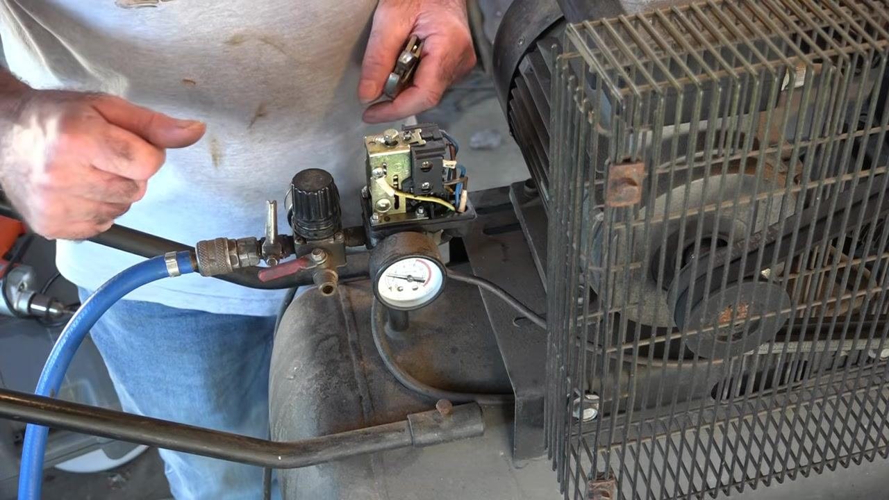 Pressure gauge on the compressor tank showing just over 50 psi, with the pressure switch exposed and the adjustment complete