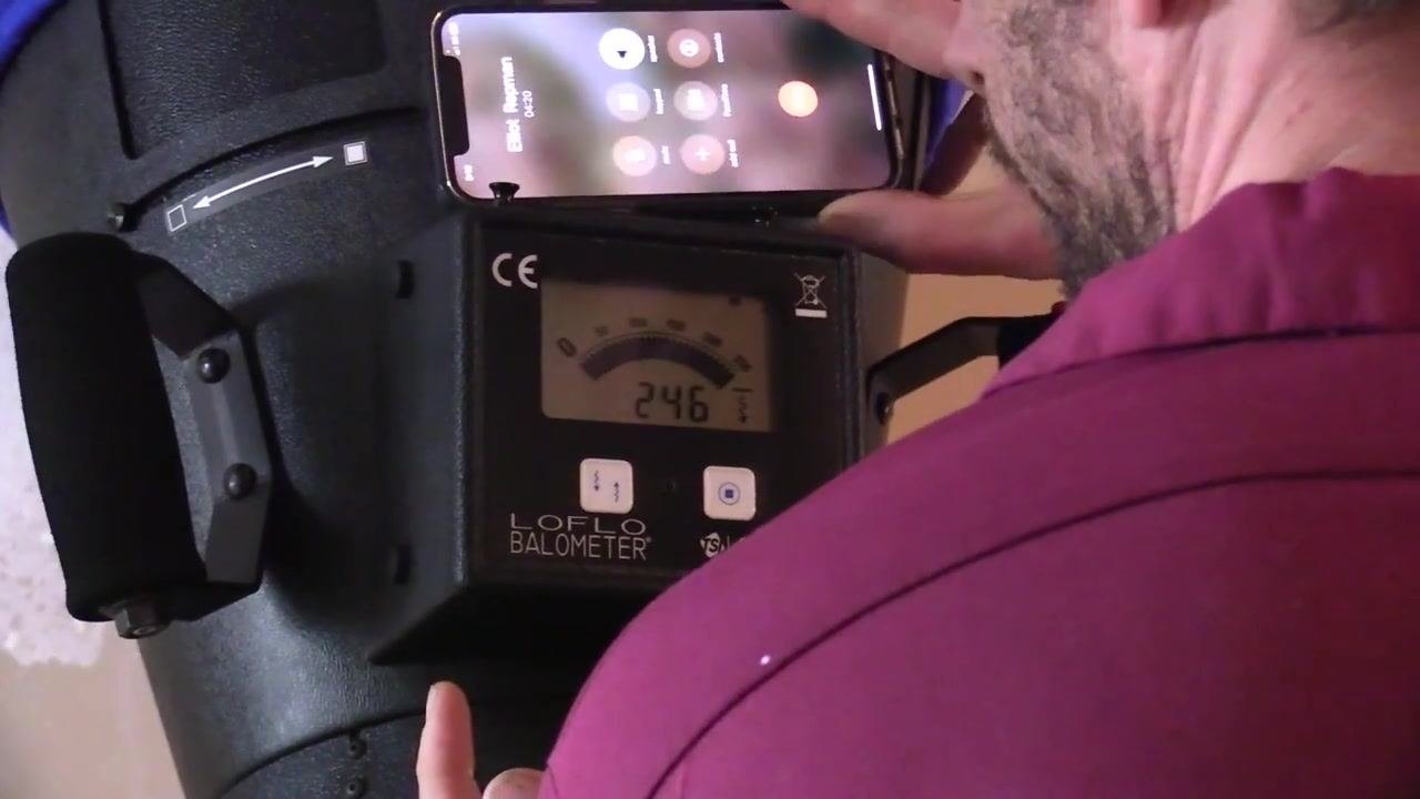 Close-up of the flow hood display showing a reading of 246 CFM while the technician communicates by phone.