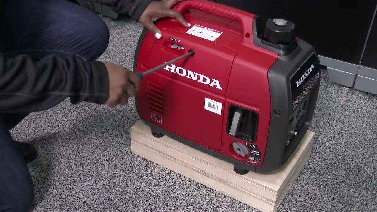Placing an oil drain pan under the generator with the maintenance cover removed