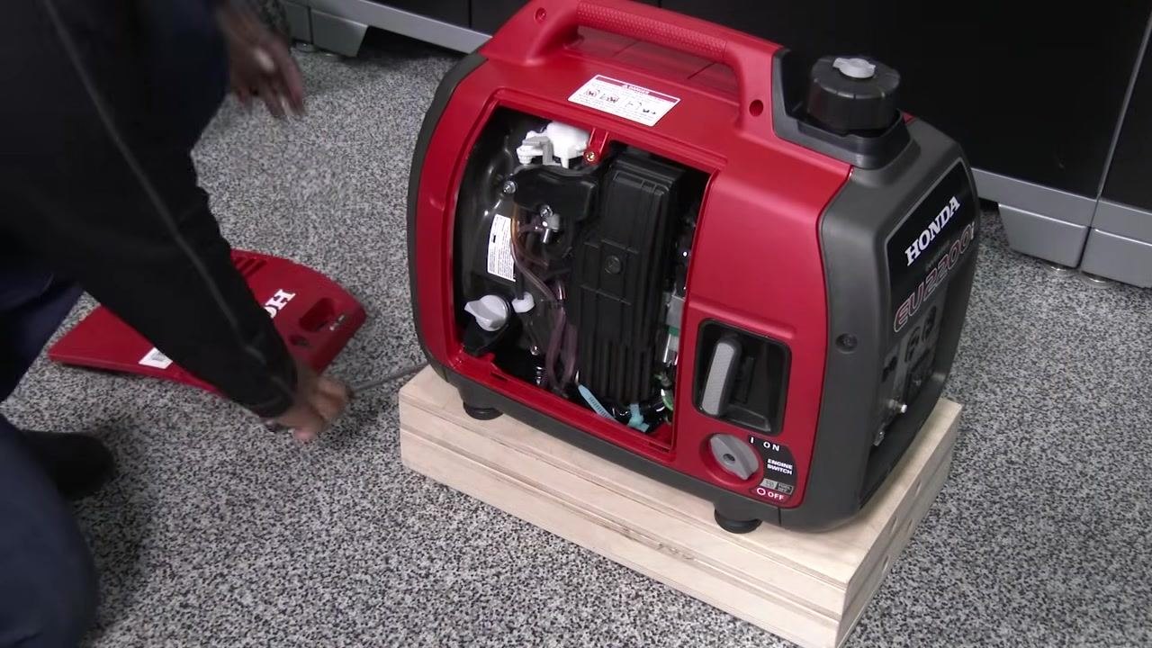 Tipping the generator to drain oil into a pan, with oil visibly flowing out
