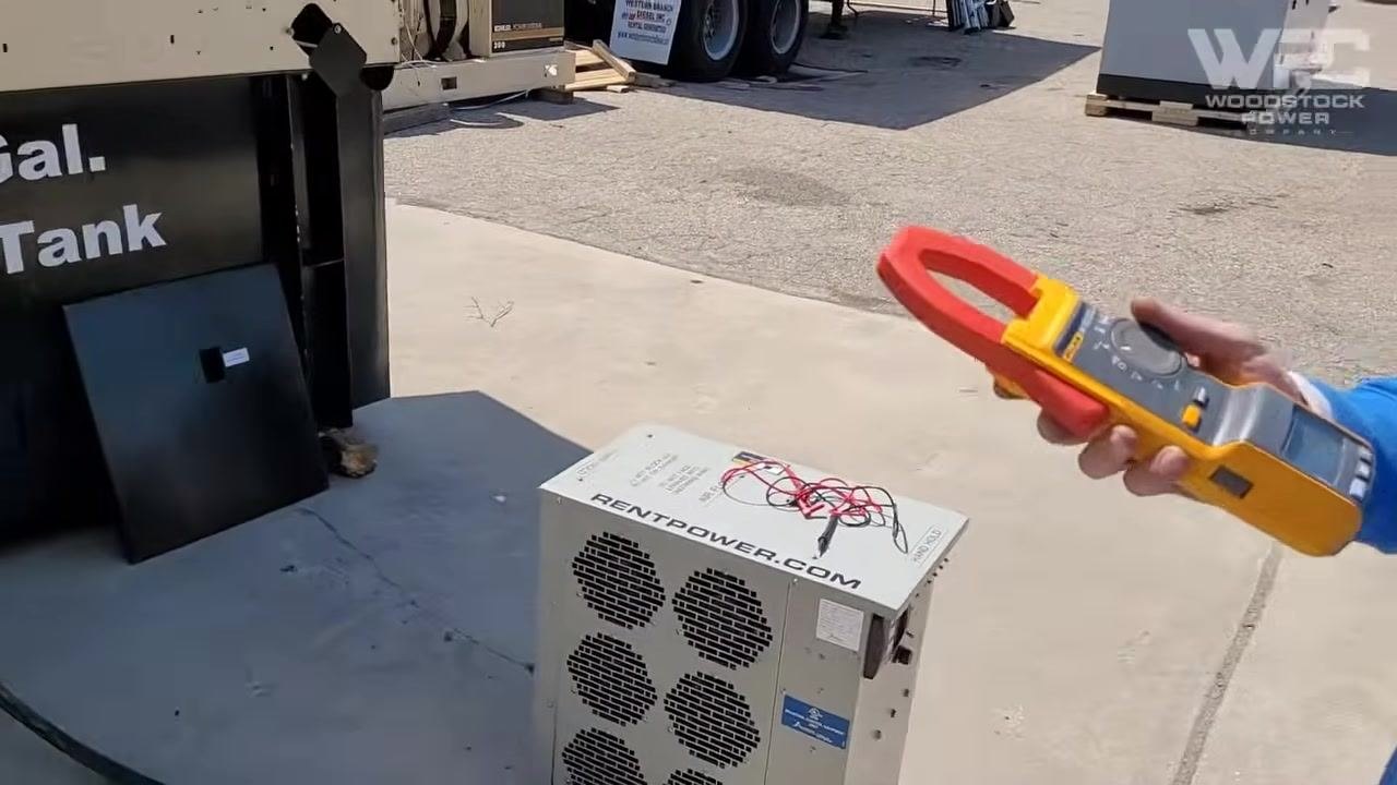 Technician holding a clamp meter, standing next to the generator, preparing to verify voltage and polarity