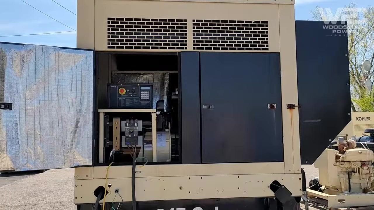 Technician standing next to the load bank, holding test leads and preparing to check voltage