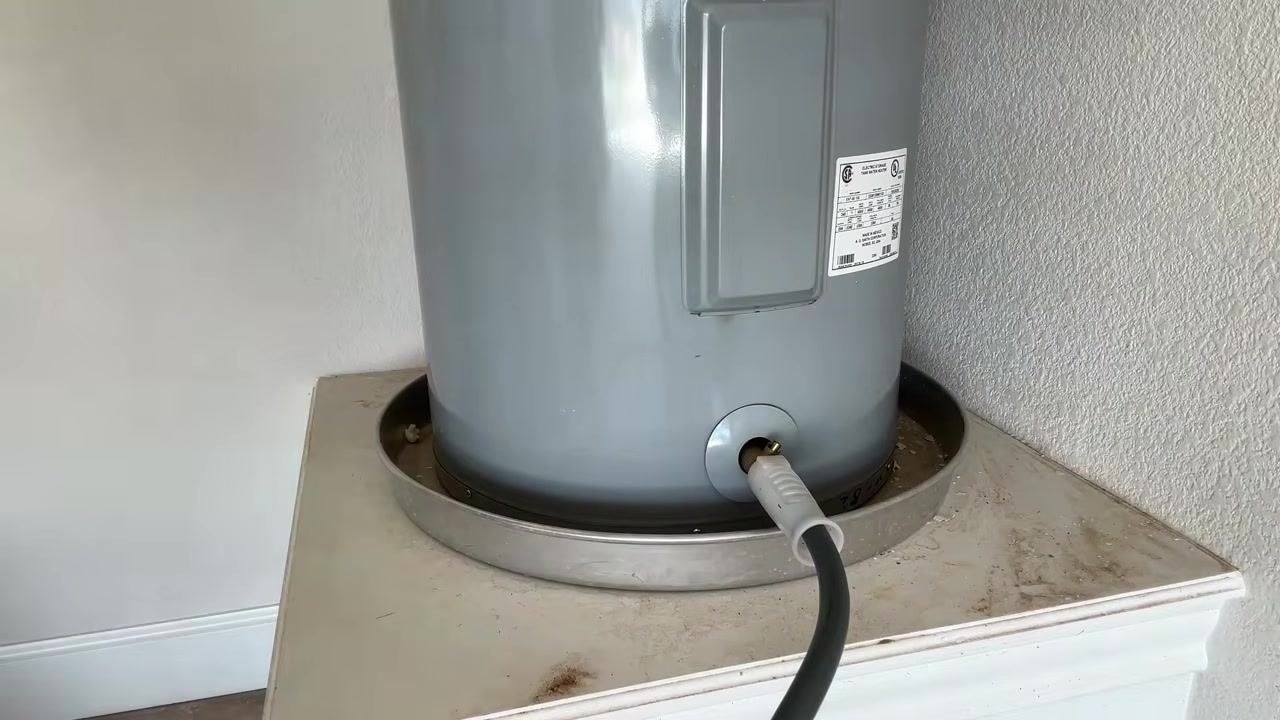 Person next to a water heater, preparing to shut off the cold water supply valve