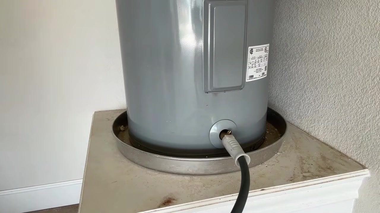 Water heater with hose attached and water draining, no person visible
