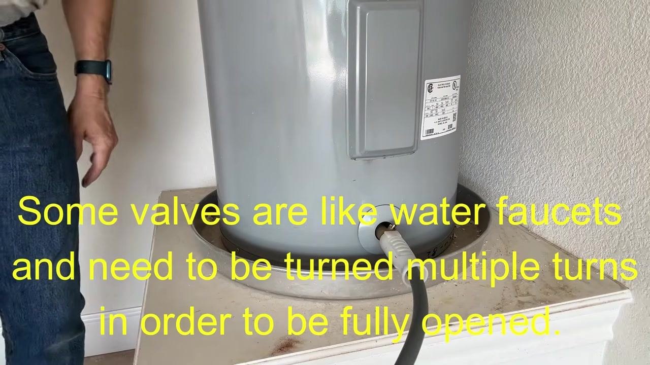 Person kneeling next to the water heater, monitoring the draining process and checking for sediment buildup