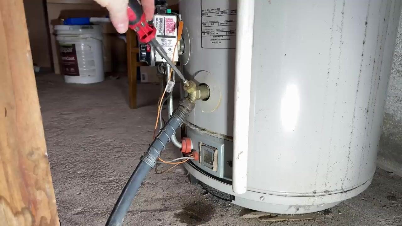 Brown water draining from a hose into a clear container, alongside a diagram showing where sediment settles at the bottom of a water heater.