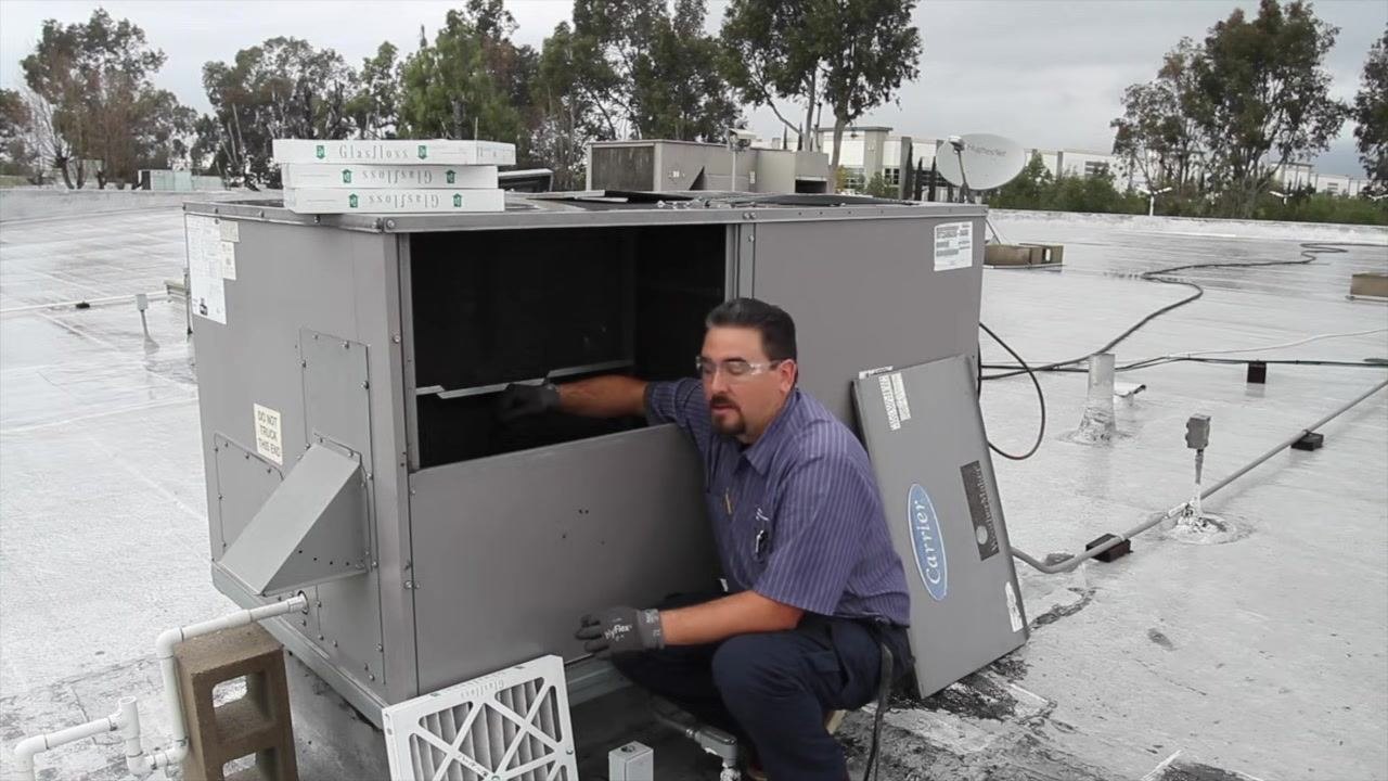 Technician removing an old air filter from the HVAC unit, with new filters ready for installation.