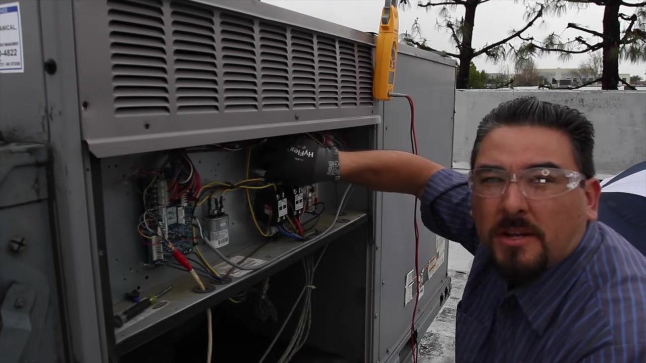 Technician closely inspecting the contactors inside the HVAC unit for signs of pitting or wear, with the electrical compartment open.