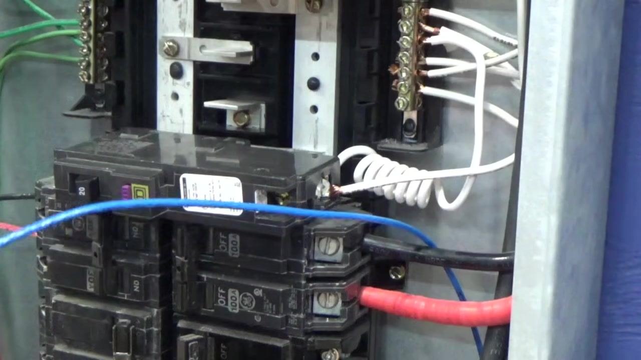 Breaker installed in the panel with the white coiled wire attached and a blue wire visible in the foreground; all connections appear secure.