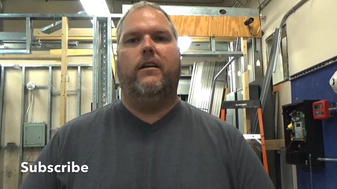 Instructor thanking viewers, standing in the workshop with electrical panels and tools in the background.