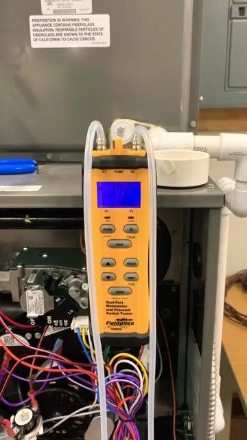 Manometer display showing a high static pressure reading of 1.29 inches, with the furnace open and tubing connected.