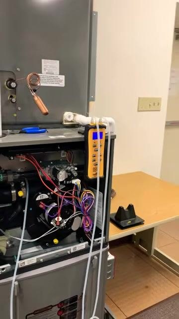 Wide view of the furnace with the manometer attached, tubing connected, and the surrounding workspace visible. The furnace remains open, showing internal wiring and components.