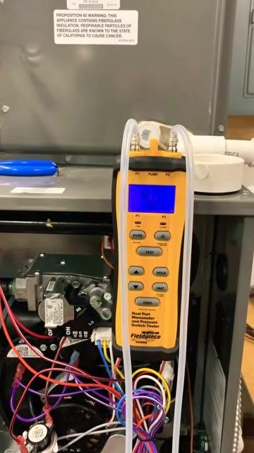 Close-up of the manometer display showing a significantly increased static pressure reading of 0.31 inches, with tubing connected and the furnace open.