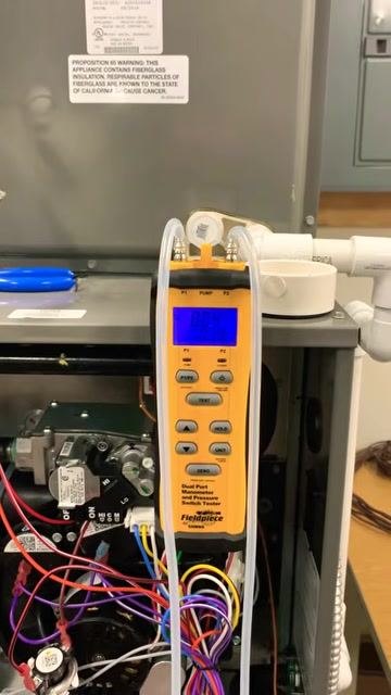 Manometer display showing a change in static pressure after blocking the return grill, with the furnace open and tubing connected.
