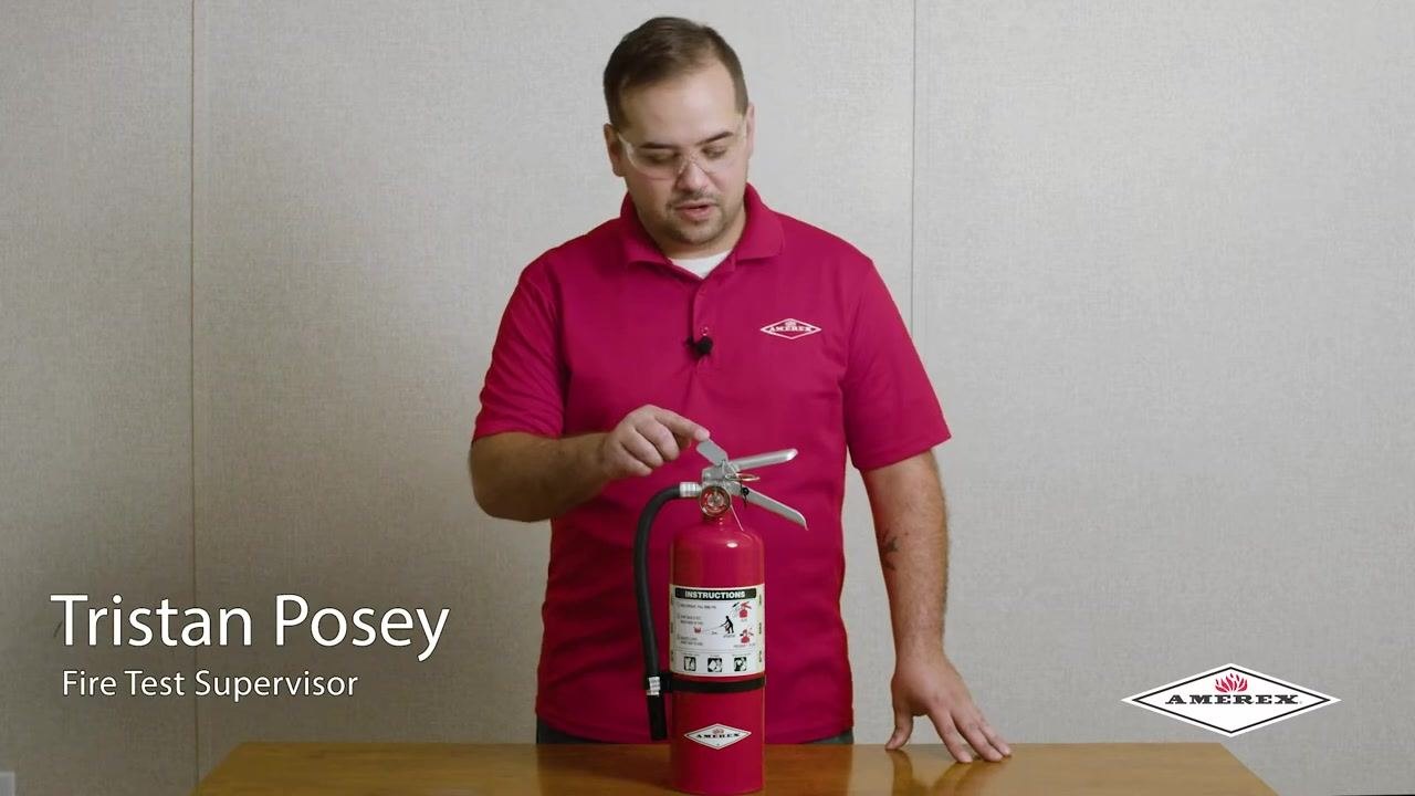 A person pointing to the pressure gauge on the fire extinguisher, demonstrating how to check the gauge reading.