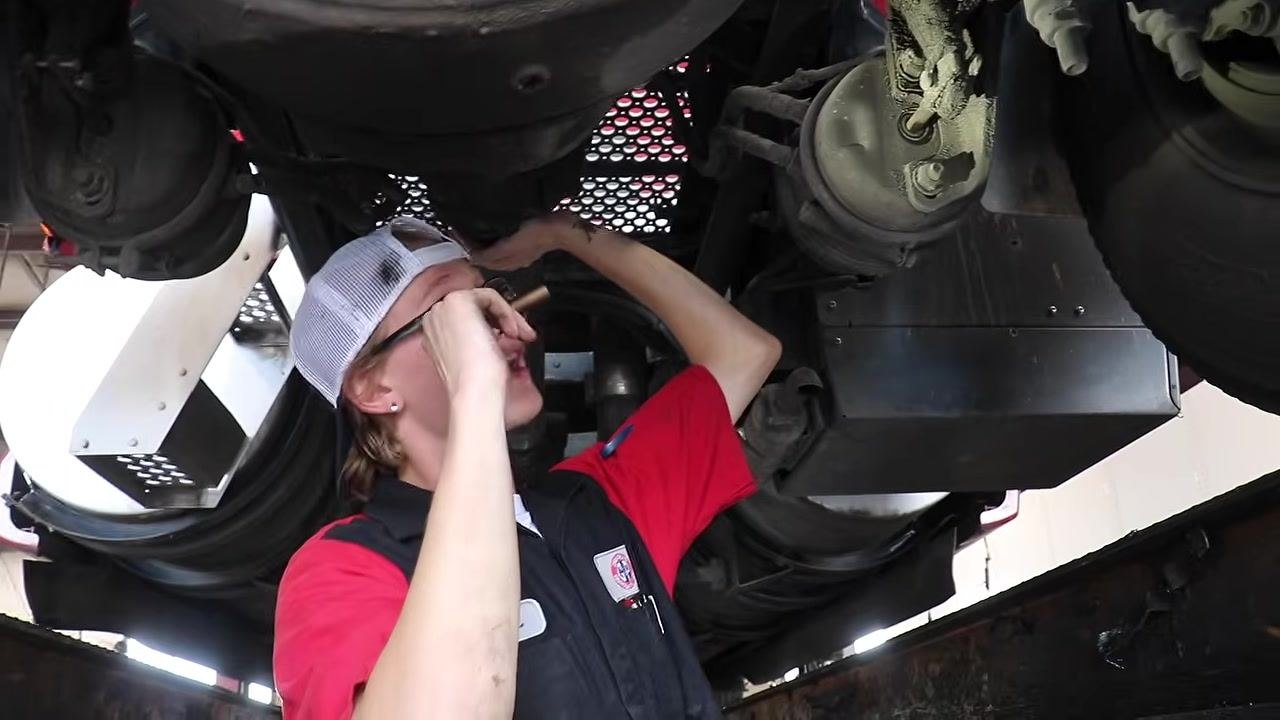 Technician inspecting the inner wheel area with a flashlight, focusing on the wheel seal for signs of leaks.