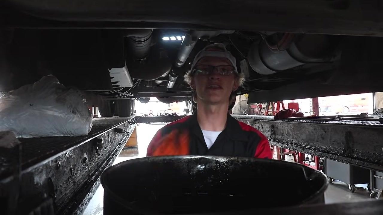 Technician holding the breaker bar, preparing to loosen the oil filter.