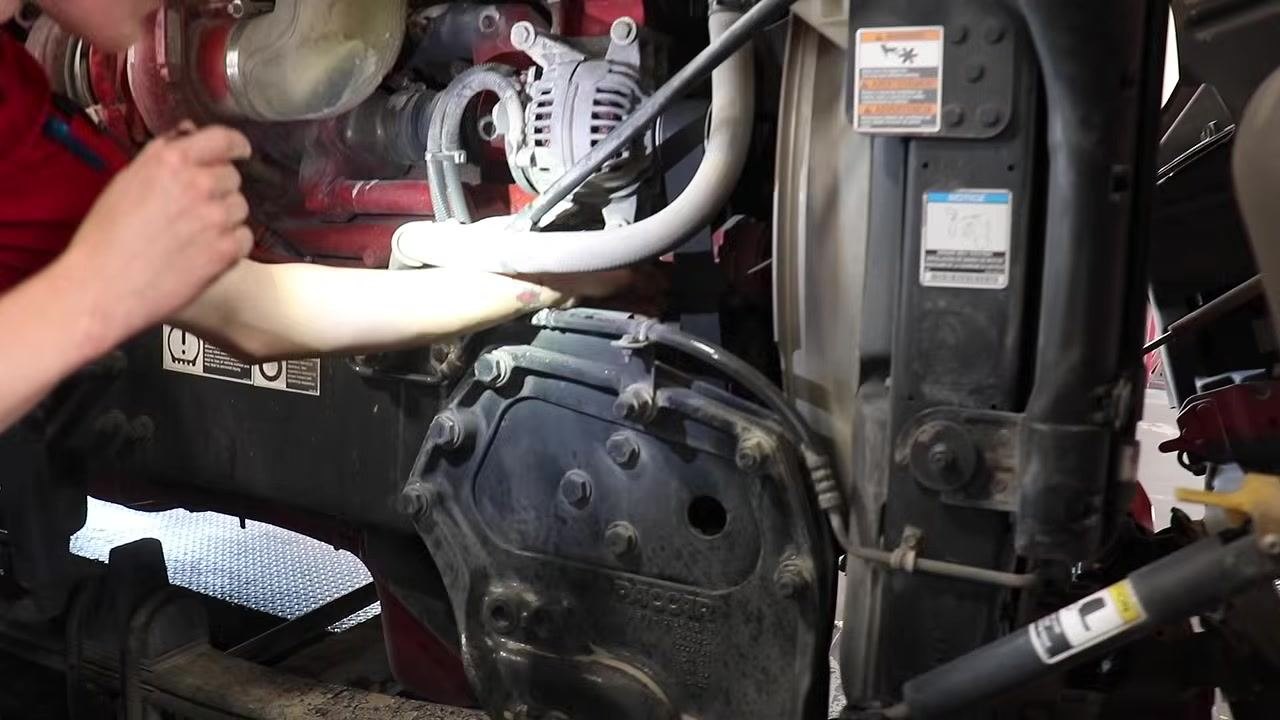 Mechanic inspecting the frame rail, springs, and U-bolts for security and damage.