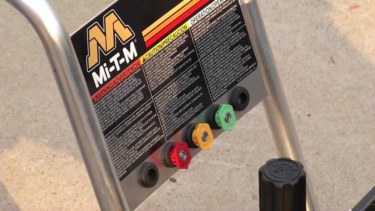 Close-up of the pressure washer's control panel showing four color-coded nozzles—red, yellow, green, and black—along with safety instructions.