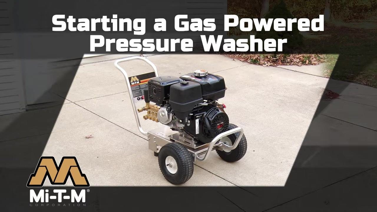 A Mi-T-M gas powered pressure washer positioned on a flat driveway, clean and ready for setup, with the Mi-T-M logo and safety instructions visible on the frame.